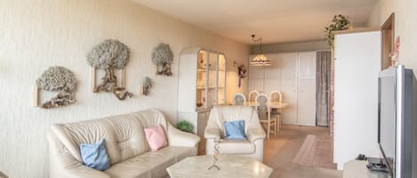 Una sala de estar con un sofá color beige, una mesa de centro y un comedor con sillas y una mesa.