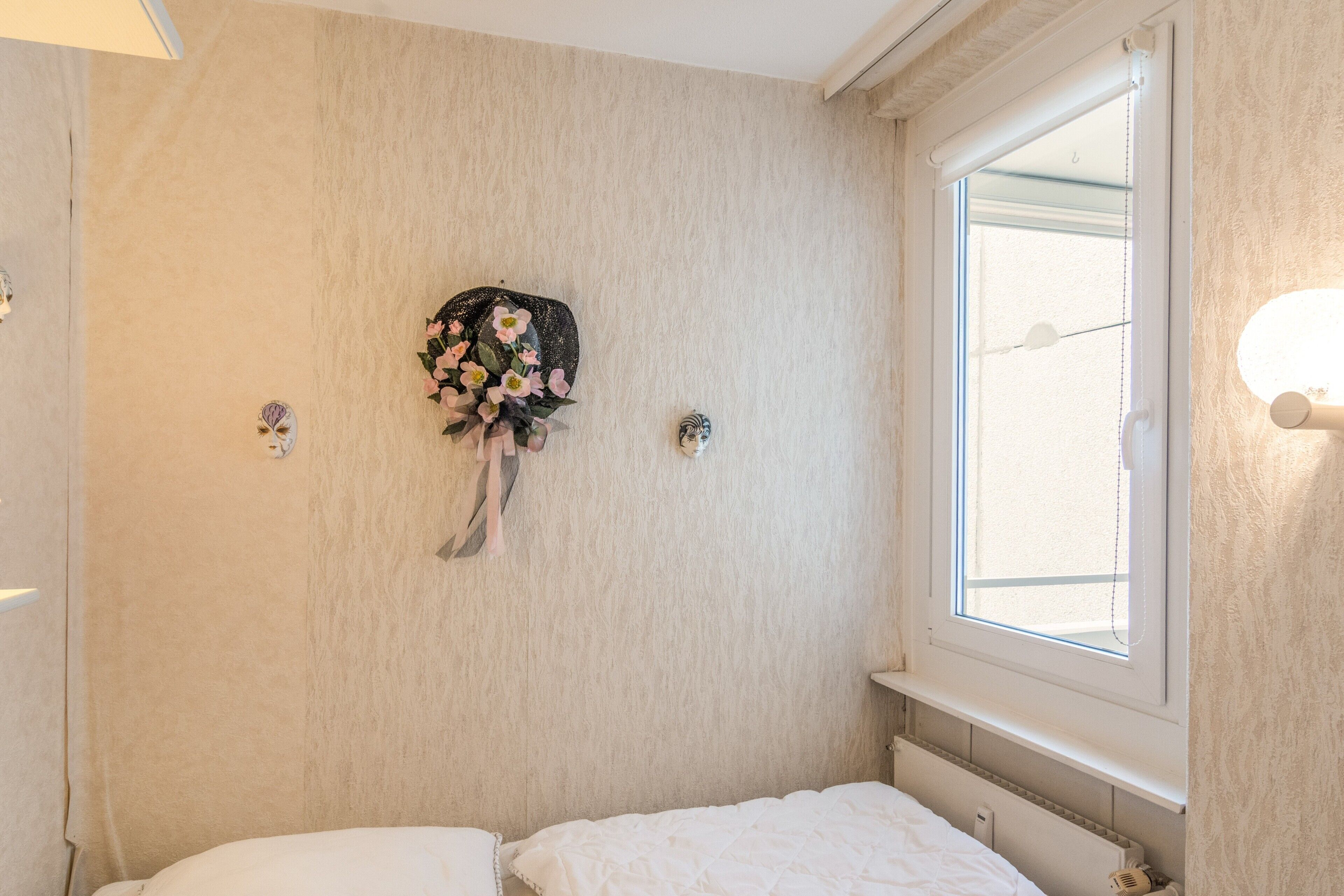 Ein Schlafzimmer mit einem Bett, einer Wanddekoration und einem Fenster.