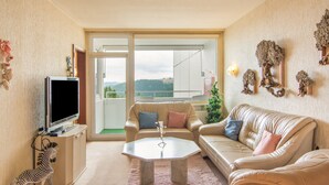 Una sala de estar con televisor, sofás, una mesa de centro y vistas al exterior.
