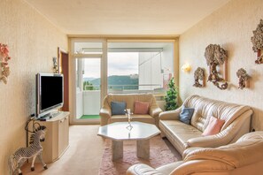 Una sala de estar con televisor, sofás, una mesa de centro y vistas al exterior.