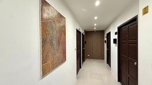 Um corredor com parede estampada, portas de madeira e chão de azulejos.