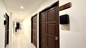 Corredor de hotel com portas fechadas, um extintor de incêndio e uma placa indicando a sala 301.