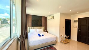 A hotel room with a bed, a window, curtains, an air conditioning unit, and a door. - King Bed Room Steps from Patong Beach (Tambon Patong)