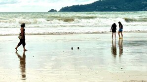 Een strand met golven en mensen die wandelen.