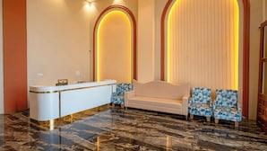A reception area with a reception desk, a sofa, and two patterned chairs. - Shree Maa Vaishno Hotel & Resort (Ujjain)