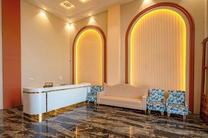 Zona de recepción con mostrador, sofá y dos sillones estampados.