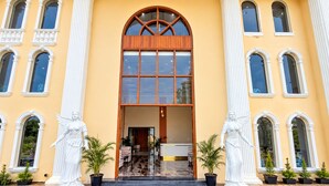 A building with a central entrance, flanked by statues, and a tiled floor.