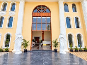 A building with a central entrance, flanked by statues, and a tiled floor. - Shree Maa Vaishno Hotel & Resort (Ujjain)
