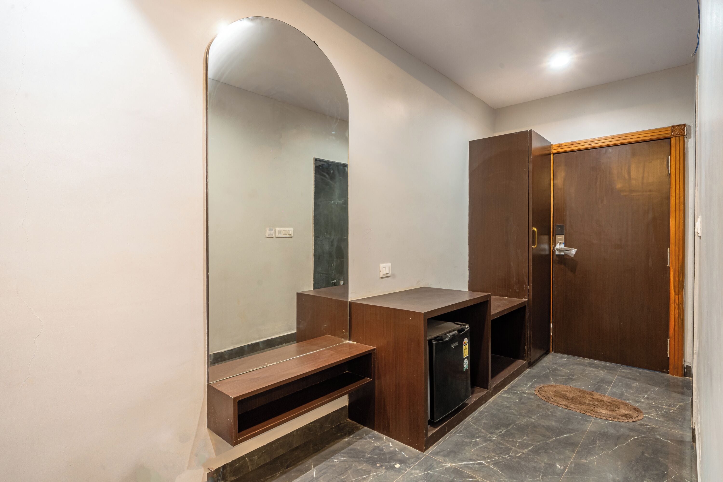 A bathroom with a large mirror, wooden vanity, and a door.