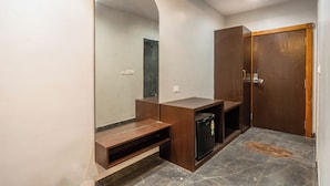 A bathroom with a large mirror, wooden vanity, and a door. - Shree Maa Vaishno Hotel & Resort (Ujjain)