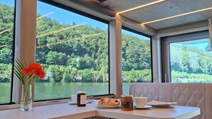 Comedor con mesa, banco y vistas a un lago rodeado de vegetación.