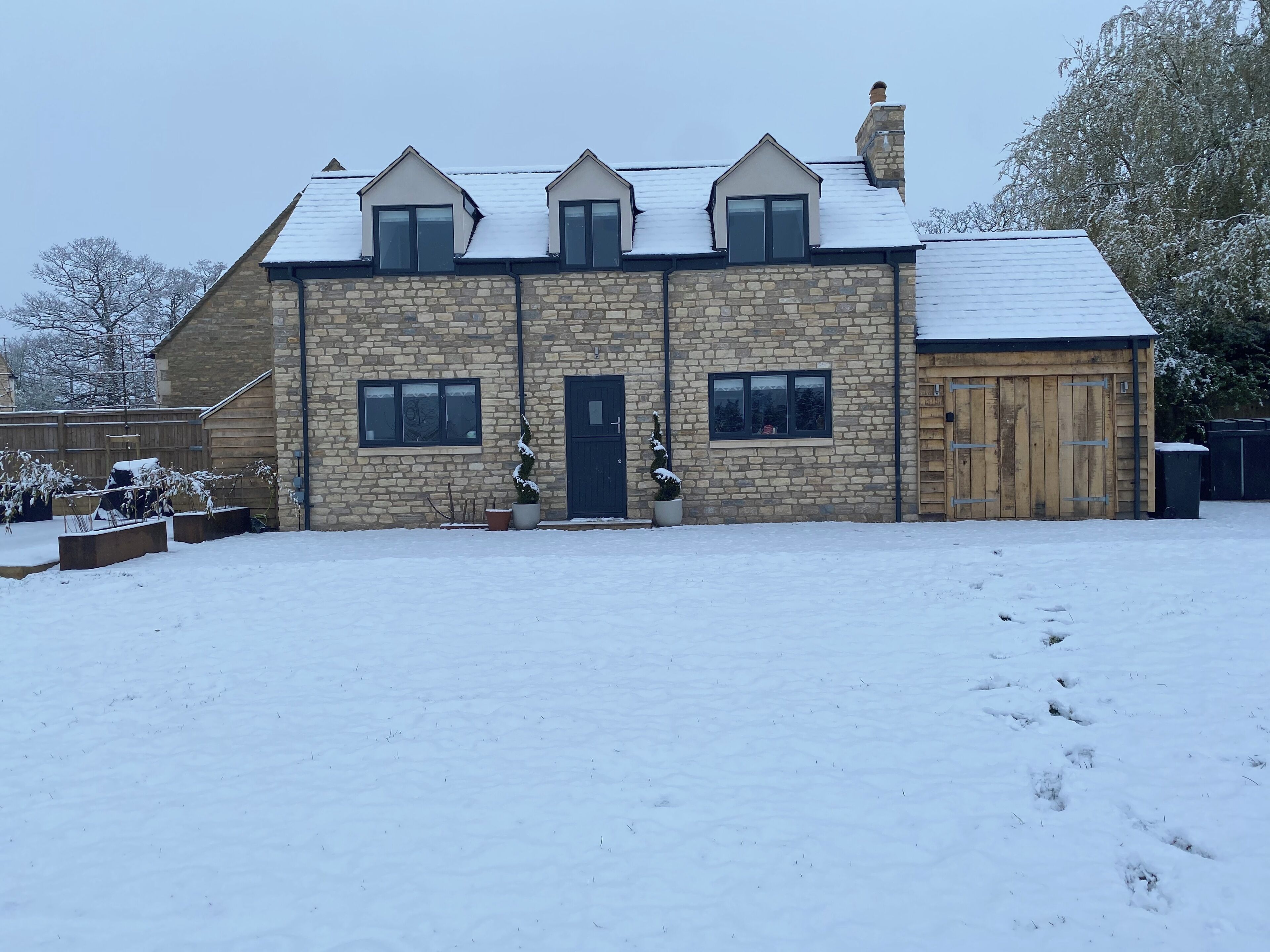 A stone building with a dark door, windows, and a garage.