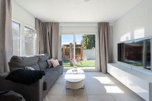 A modern living room with a grey sofa, a white coffee table, and a flat-screen TV. - Villa Linn - Modern Family Villa in Mijas (Mijas)