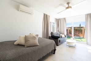 Une chambre d’hôtel avec un lit, un canapé, une petite table et un ventilateur de plafond.