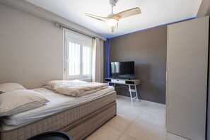 A bedroom with a bed, a TV, and a ceiling fan. - Villa Linn - Modern Family Villa in Mijas (Mijas)