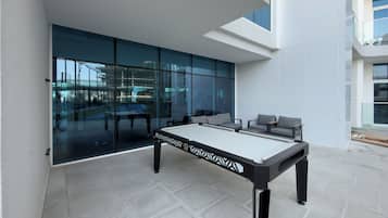 A pool table in a modern indoor space with glass walls and a view of the outside.