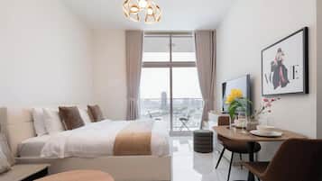 Quarto de hotel moderno com uma cama grande, um espaço de jantar e vista para a cidade.