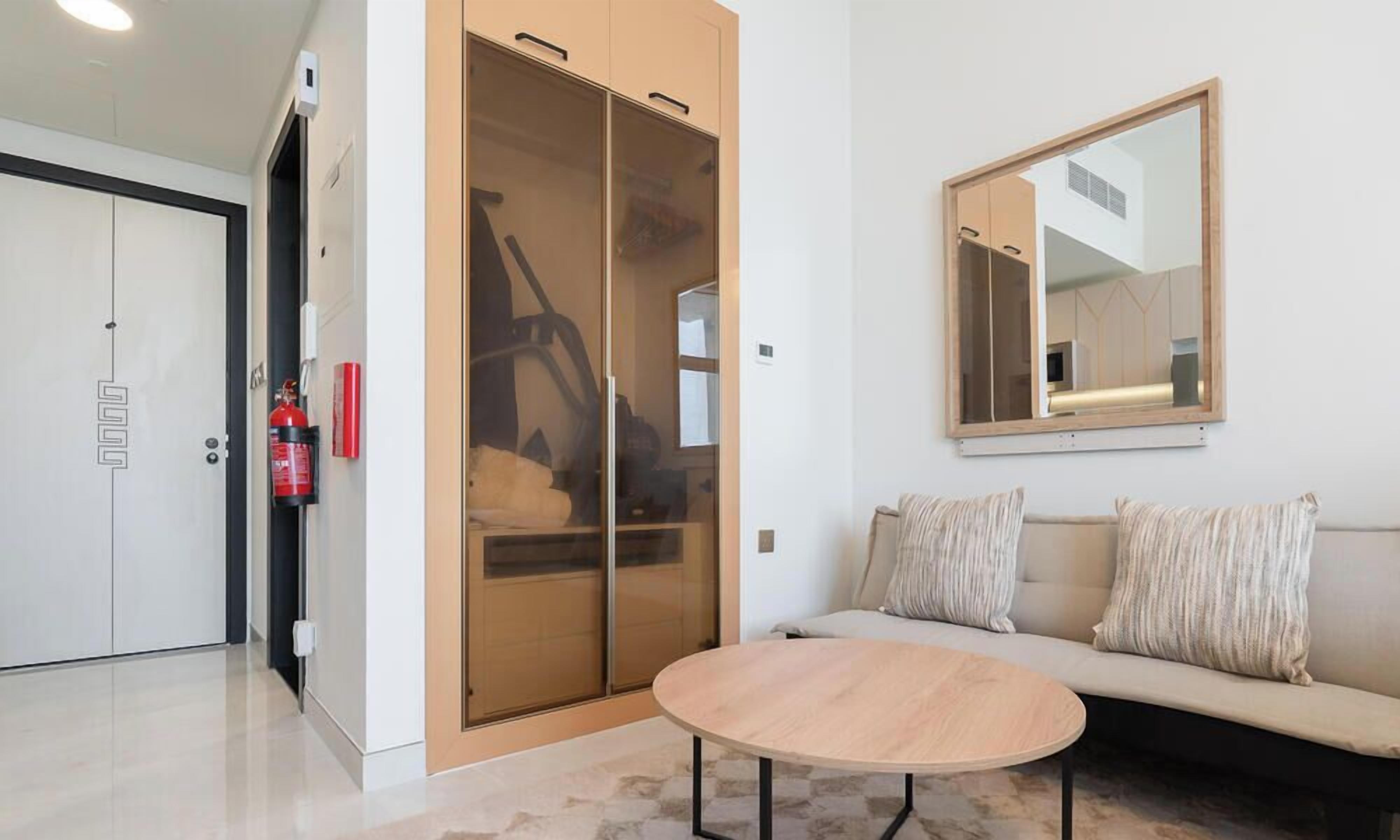 Een moderne kamer met een bank, een ronde tafel, een schuifdeurkast en een wandspiegel.