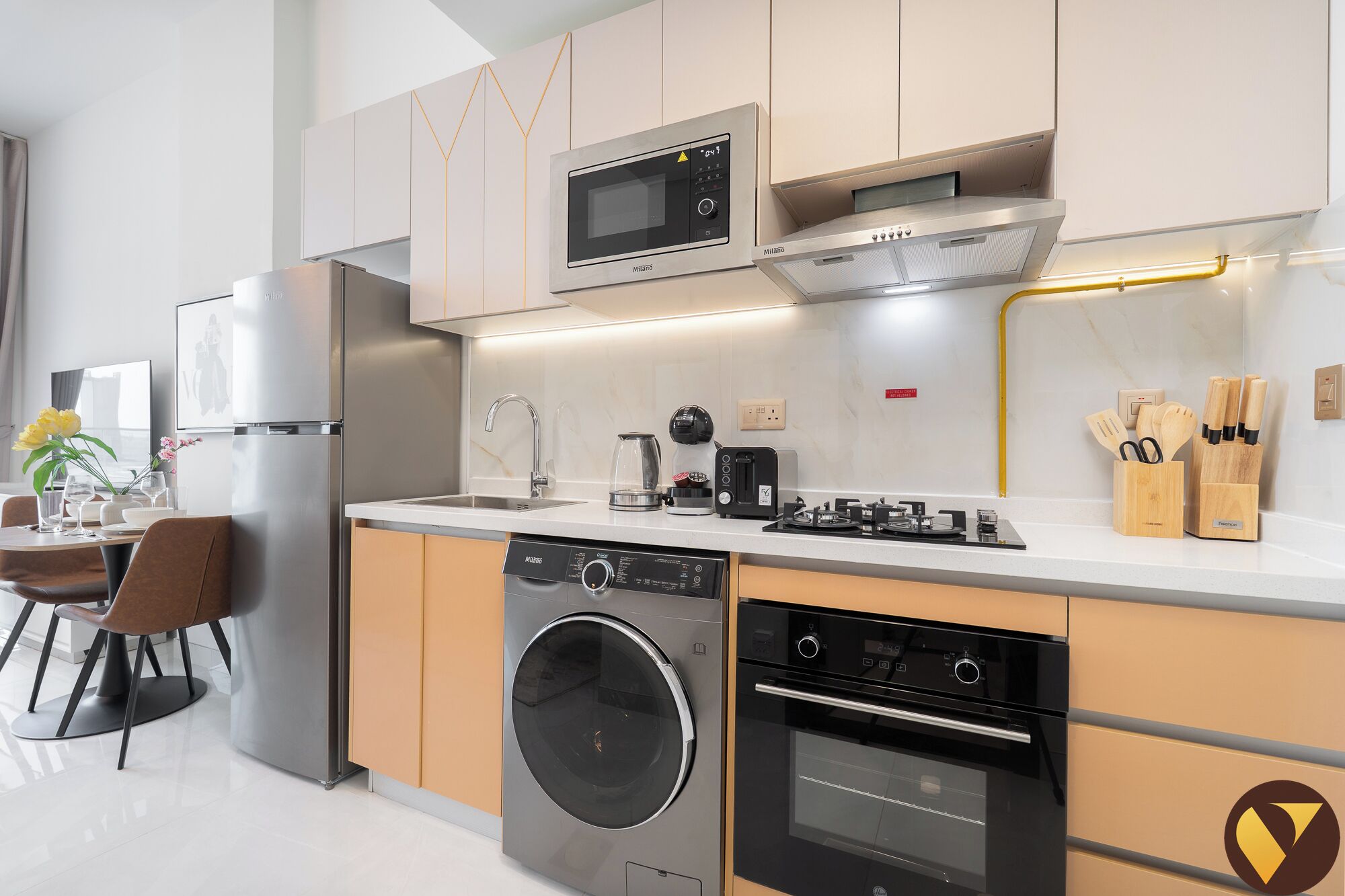 Uma cozinha moderna com máquina de lavar integrada, forno, micro-ondas e cafeteira na bancada.