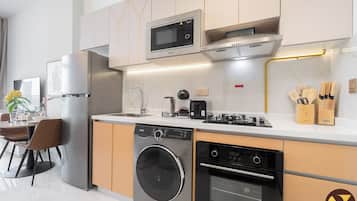 Uma cozinha moderna com máquina de lavar integrada, forno, micro-ondas e cafeteira na bancada.