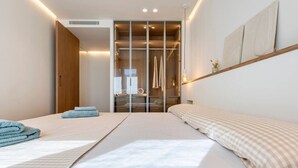 A modern hotel room with a large bed, a walk-in closet, and a view of the city. - Can Costelles II - Mediterranean Gem with Sea View (Cambrils)