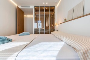 Ein modernes Hotelzimmer mit einem großen Bett, einem begehbaren Kleiderschrank und Blick auf die Stadt.