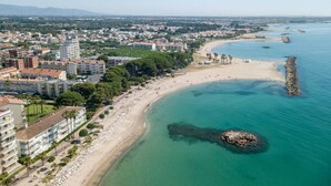 A coastal cityscape with a sandy beach, a rocky outcrop, and residential buildings. - Can Costelles II - Mediterranean Gem with Sea View (Cambrils)