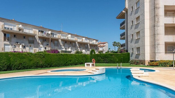 A swimming pool with a lifebuoy, surrounded by a hedge and a building with balconies. - Can Costelles II - Mediterranean Gem with Sea View (Cambrils)