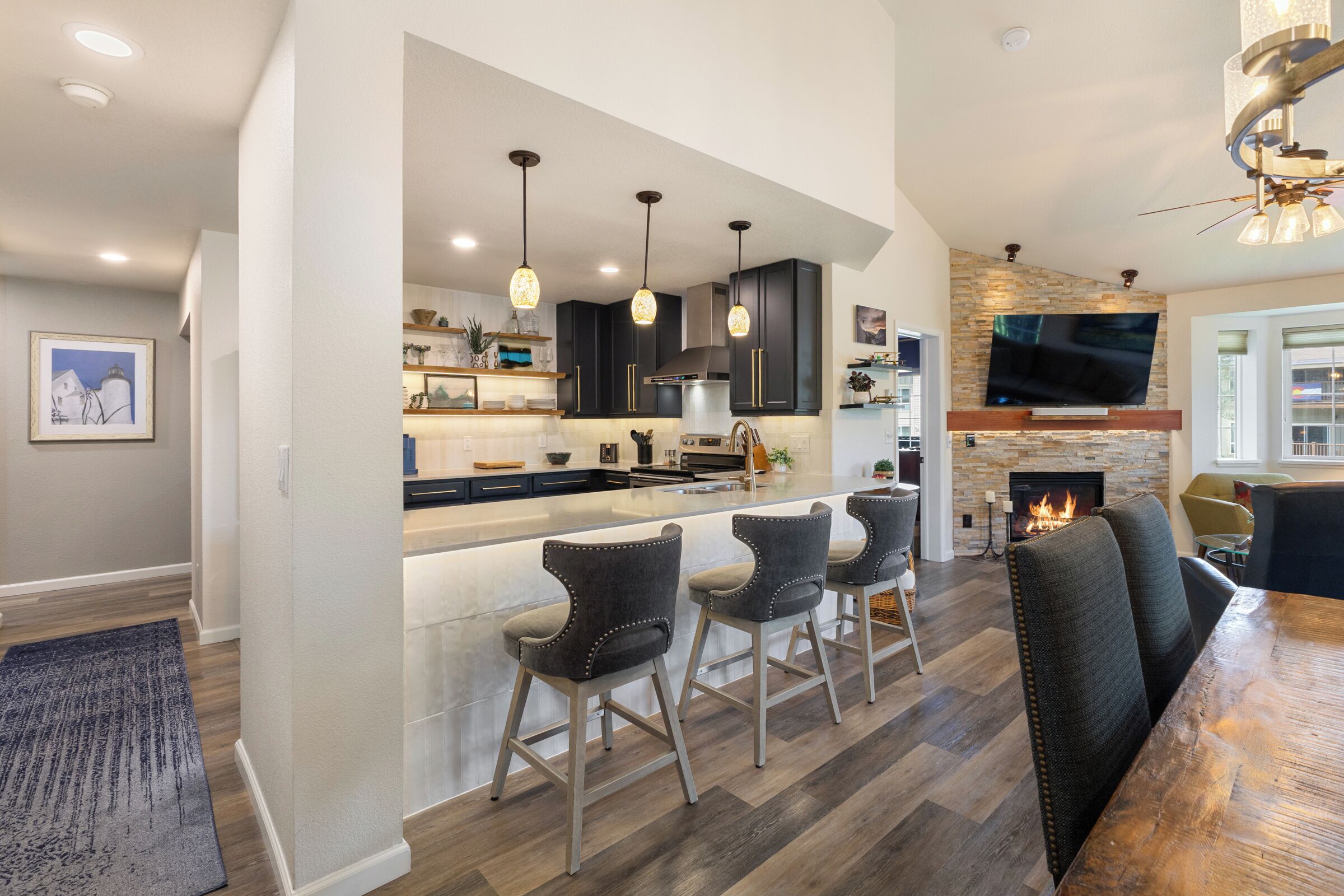 A modern kitchen with dark cabinetry, pendant lighting, and a central island with bar stools.