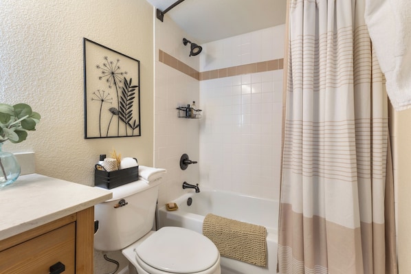 A bathroom with a toilet, sink, shower, and a framed artwork on the wall. - 1 Car Garage | Gourmet Kitchen | On Bus Route (Steamboat Springs)