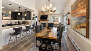 A modern kitchen with dark cabinets, a central island, and pendant lighting. - 1 Car Garage | Gourmet Kitchen | On Bus Route (Steamboat Springs)