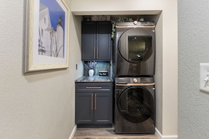 A compact laundry area with a washing machine and dryer, a small cabinet, and a framed picture on the wall. - 1 Car Garage | Gourmet Kitchen | On Bus Route (Steamboat Springs)