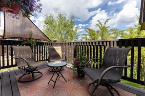 A wooden deck with outdoor furniture, including chairs and a table, and a view of trees and sky. - 1 Car Garage | Gourmet Kitchen | On Bus Route (Steamboat Springs)