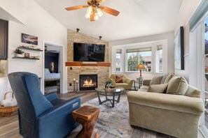 A modern living room with a fireplace, a flat-screen TV, comfortable seating, and a view of the outdoors. - 1 Car Garage | Gourmet Kitchen | On Bus Route (Steamboat Springs)