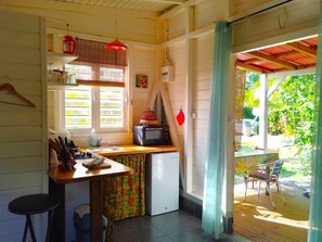 A compact kitchen with a refrigerator, microwave, and a small dining table. - Kaz Kokonut, a Creole bungalow on Marie-Galante (Saint-Louis)