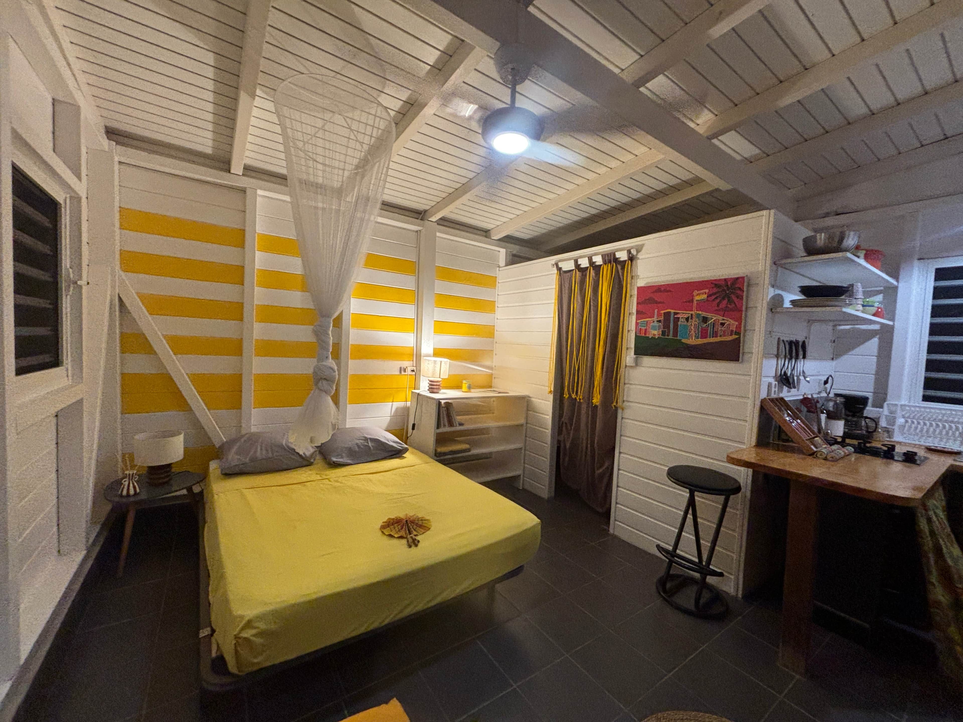 A room with a bed, bedside table, and a desk with a chair.