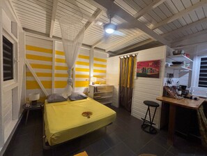 A room with a bed, bedside table, and a desk with a chair.