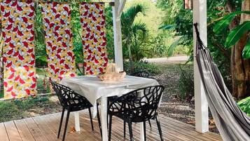 Une terrasse extérieure avec une table et des chaises, un hamac et un toit rouge.
