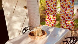 An outdoor dining area with a table covered by a white tablecloth, two black chairs, and a woven basket on the table.
