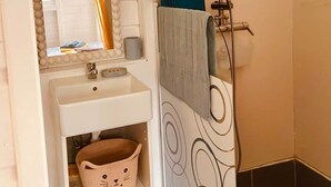 A bathroom with a white sink, a mirror with a beaded frame, a towel rack, and a shower with a blue curtain.