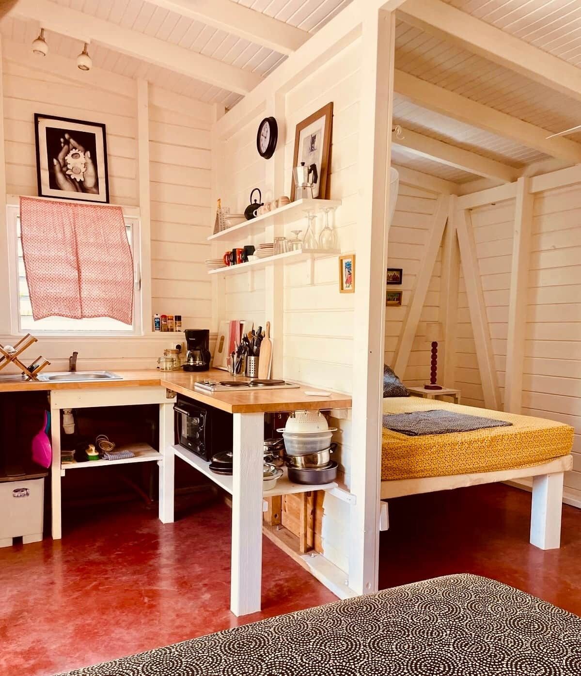 Habitación compacta y de diseño abierto con kitchenette, una cama con colchón amarillo y un tapete estampado.