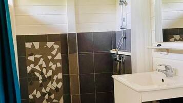 A bathroom with a shower, a sink, and a tiled wall.