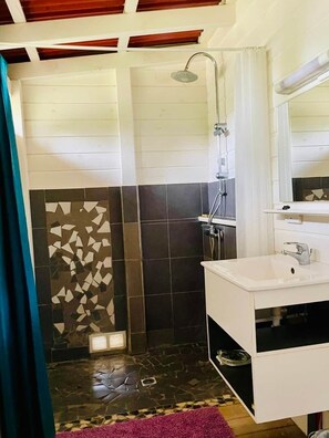 A bathroom with a shower, a sink, and a tiled wall. - Kaz Papaya, a Creole bungalow on Marie-Galante (Saint-Louis)
