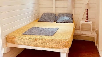 A bed with a canopy, two pillows, a bedside table, and a picture on the wall.