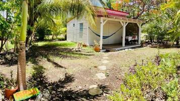 A small house with a porch, surrounded by tropical vegetation.