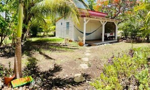 A small house with a porch, surrounded by tropical vegetation.