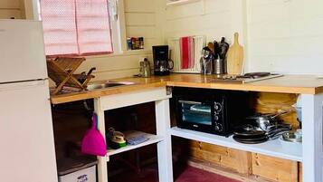 A compact kitchen with a refrigerator, a microwave, a sink, and a wooden countertop.