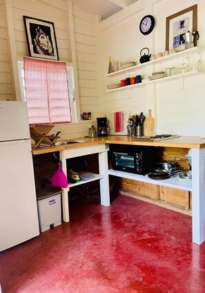 A compact kitchen with a refrigerator, a microwave, a sink, and a wooden countertop.