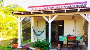 A covered outdoor seating area with a table and chairs, a hammock, and potted plants. - Kaz Papaya, a Creole bungalow on Marie-Galante (Saint-Louis)