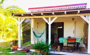 A covered outdoor seating area with a table and chairs, a hammock, and potted plants. - Kaz Papaya, a Creole bungalow on Marie-Galante (Saint-Louis)